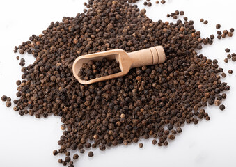black pepper peas in a wooden spoon and scattered isolated on a white background