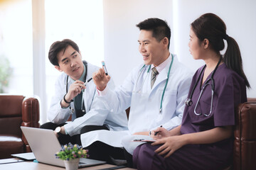 Asian medical team is discussing the vaccine test results for treatment of patients infected Covid-19, Young doctor holding test tube blood sample was vaccinated and explained information in laptop.