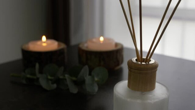 Aroma candles with reed diffuser on table in room