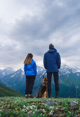 Fototapeta na wymiar A girl and man travelers with a dog stay in the mountains, Georgia, Svaneti