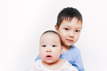 Portrait of Asian siblings. Elder brother hugging his little sister. Cute children. Family relations. White background. Surprised baby.