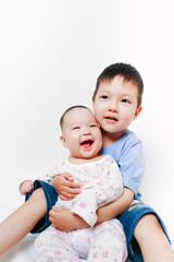 Portrait of Asian siblings. Elder brother hugging his little sister. Cute children. Family relations. White background. Smiling baby.