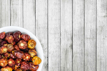 A bunch of round red chillies in white bowl in a nice wooden background