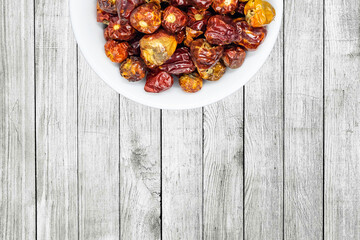 A bunch of round red chillies in white bowl in a nice wooden background