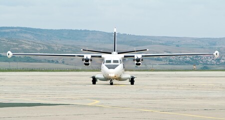 Front view of business jet airplane is taxiing on the apron after landing with rotating propeller,...