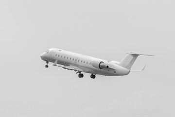 Flying airplane after taking off. White commercial passenger jet airliner in flight, no painting. Modern technology in fast transportation, business travel and tourism, aviation.