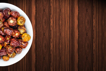 A bunch of round red chillies in white bowl in a nice wooden background