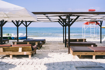 Obraz na płótnie Canvas beach with wooden arbors, white umbrellas and a path 