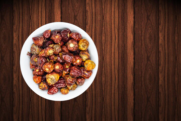 A bunch of round red chillies in white bowl in a nice wooden background