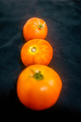 three tomatoes with selective focus in black background