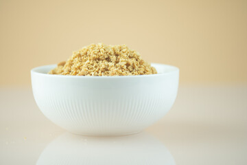 Bowl of roasted crushed peanuts on white background.