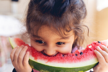 Little girl eating watermelon. The girl is two years old. Summer heat
