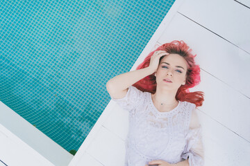 beautiful girl with pink hair lies near the pool and looks up
