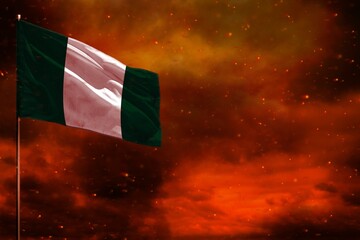 Fluttering Nigeria flag mockup with blank space for your text on crimson red sky with smoke pillars...
