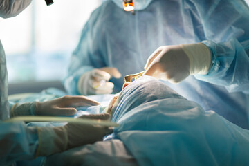 Surgeon and his assistant performing cosmetic surgery on nose in hospital operating room. Nose...