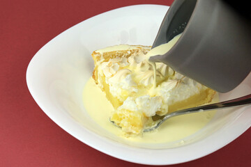 Fototapeta na wymiar Fresh cream being poured over a lemon meringue pie .