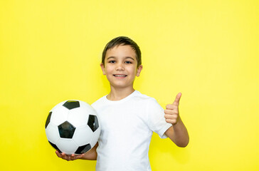 Portrait of an emotional child A boy holds a ball in his hand. Baby girl in a white T-shirt on a yellow background. Place for text