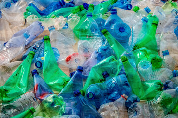 A mountain of green and blue plastic bottles that are packed and bumped tightly together