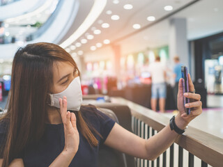 Women wearing mask and holding the smartphone in the supermarket.