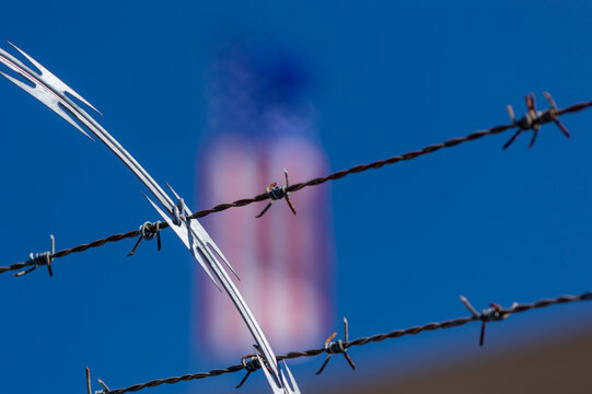 Razor wire and barbed wire in front of American flag