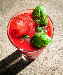 Tomato juice with ice and basil outside