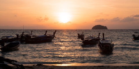Seashore in the moment of sunset is surrounding by Thailand taxi boats.