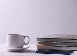 a white ceramic cup with tea or coffee and a saucer on the light background