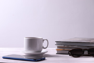 a white ceramic cup with tea or coffee and a saucer on the light background
