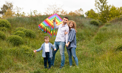 Portrait of happy family with bright kite in countryside