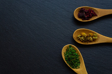 Spices background on wooden spoons. Parsley, chamomile, hibiscus