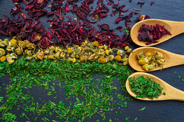 Spices background on wooden spoons. Parsley, chamomile, hibiscus