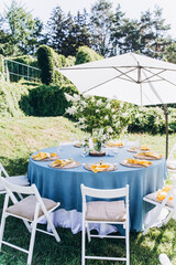 Banquet table setting and decoration. Cutlery on the table. Blue interior decoration. Tables at the outdoors.
