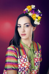 Portrait of a cute girl with bright makeup and with the blooming freesias on his head and hands on a red background in the Studio.