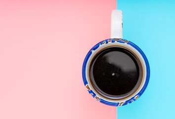 Cup of coffee on a gently pink and turquoise background. Top view flat lay.