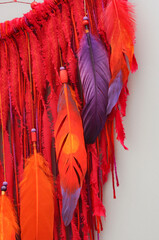Native dream catcher with painted feathers on gray background