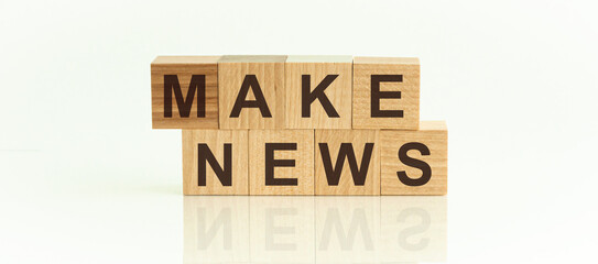 MAKE NEWS - text on wooden cubes on a white gradient background.