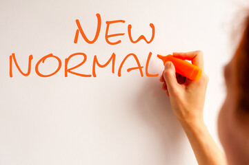 Hand writing inscription New normal with marker, concept. orange marker, orange letters