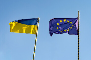 Fototapeta Flags of Ukraine of the European Union. Two flags on the background of a beautiful blue sky and trees. obraz