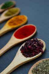 spice background on wooden spoons. Seasoning texture. Hibiscus, black pepper, paprika, cumin, curry, parsley