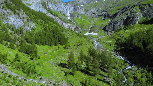 Aerial: drone flying over scenic high waterfall lush green valley and mountain stream on the italian Alps. Tourism destination hiking outdoors activity. Pis waterfall near Torino, Piedmont, Italy