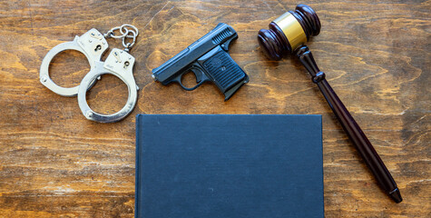 Law, crime, punishment concept. Judge gavel, handgun, handcuffs and a black blank legal book on...