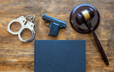 Law, crime, punishment concept. Judge gavel, handgun, handcuffs and a black blank legal book on...