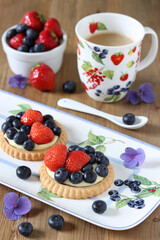 Heidelbeer-Erdbeer-Tartelettes auf Kuchenplatte