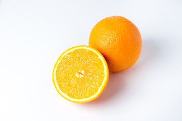 Oranges on a white background. One orange is whole, the other is cut in half. Tropical fruits