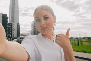 Fototapeta premium Adult woman with a beautiful smile blond hair makes selfie on a smartphone.