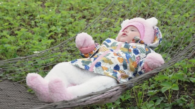 A little child sways on a hammock and quietly smiles.