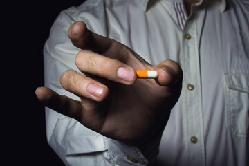 Fototapeta premium Male hand holds a pill. A man in a white shirt. Medicine for business.