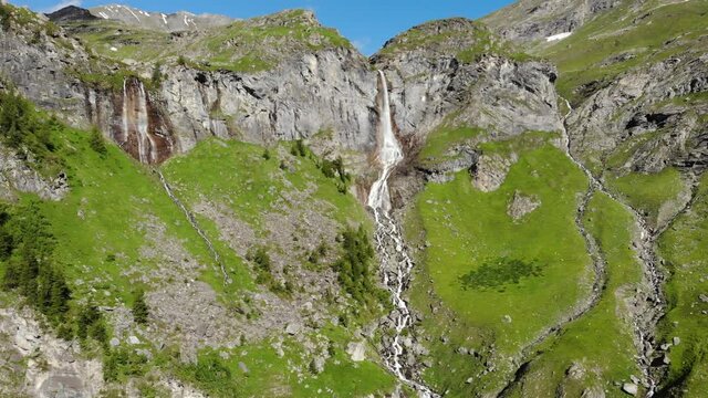 Aerial: drone flying over scenic high waterfall, mountain stream falling from tall rocky cliff on the italian Alps. Pis waterfall near Torino, Piedmont, Italy. Native d-log color profile