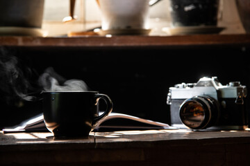 morning light refreshing black cup of hot coffee and stream with silver vintage camera and white page writing diary on wood table focus on cup stock photo