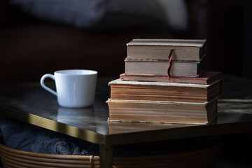 Naklejka premium A stack of old books with a white cup next to it